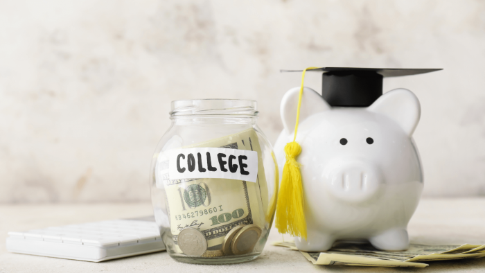 jar with money inside next to piggy bank wearing graduation cap