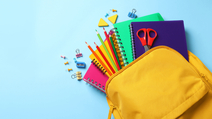 Backpack with school supplies on flat surface