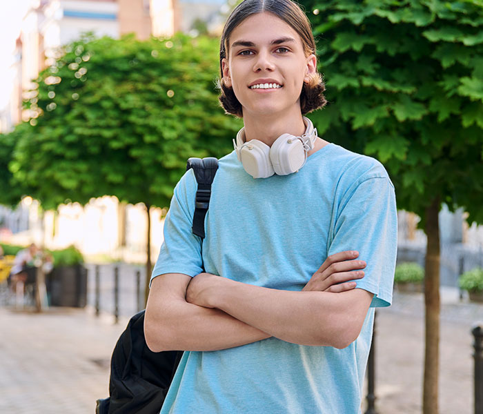 Young man with crossed arms and headphones around his neck wearing a blue t shirt
