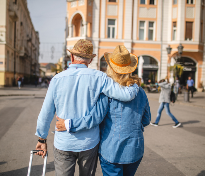 Mature couple walking in European city with suitcase