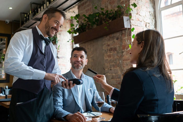 Man and woman at restaurant paying server with a debit card