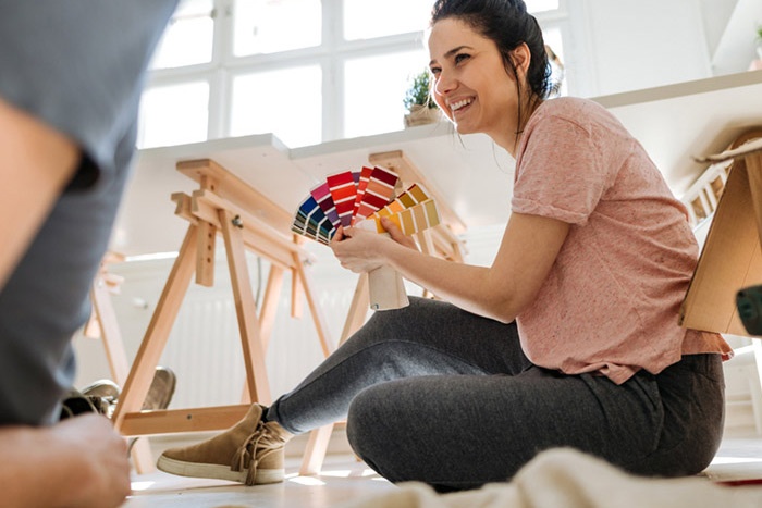 Woman sitting on floor of her house looking at paint swatches