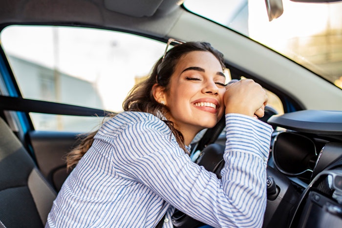 Woman smiling while leaning her head on dash of her car