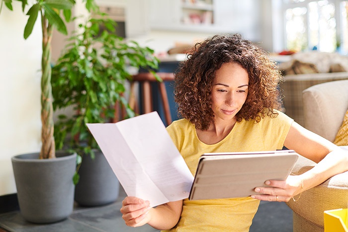 Woman with document looking at tablet