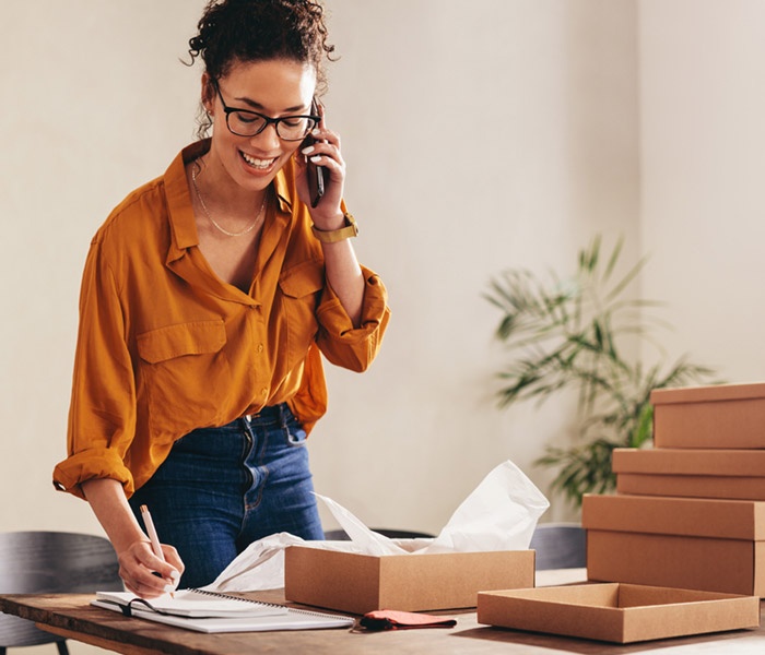 Woman talking on cell phone and taking order for her retail business.