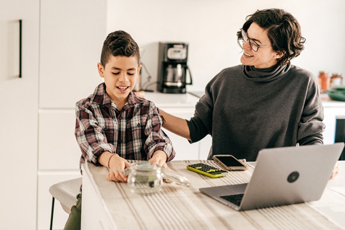 Mom and son sitting at table counting his savings