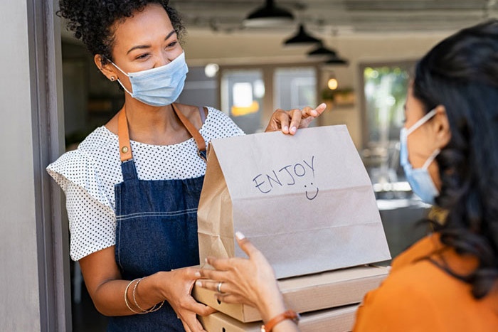 Woman at restaurant giving carryout order to customer