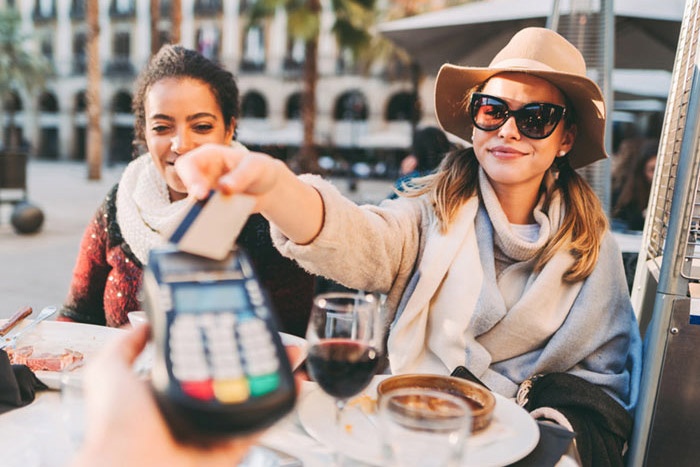 Two women having lunch paying with debit card
