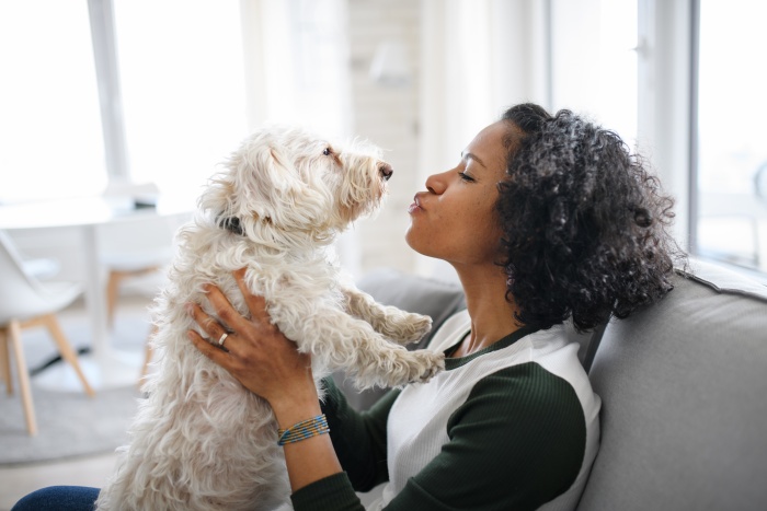 woman sitting on couch making kissy face at her dog