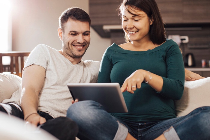 Couple sitting on couch looking at tablet