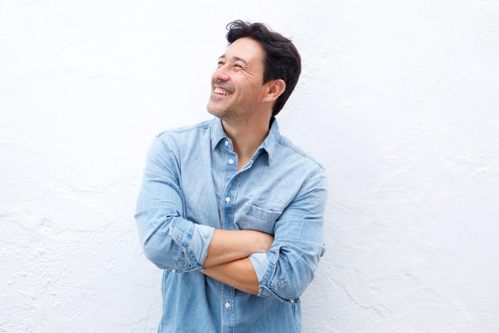 Middle-aged man smiling, crossing arms and looking upward