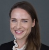 Natalie Sakar, a brunette woman with blue eyes and raspberry lipstick smiling at the camera