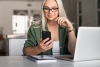 Woman sitting at desk at home looking at her phone