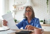 woman sitting at desk in her home looking at paper and calculator